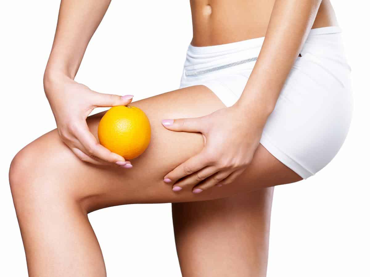 Female squeezes cellulite skin on her legs – close-up shot on white background